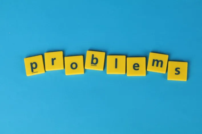 Yellow letter tiles spelling 'problems' arranged on a vibrant blue background, creating a textual concept image.