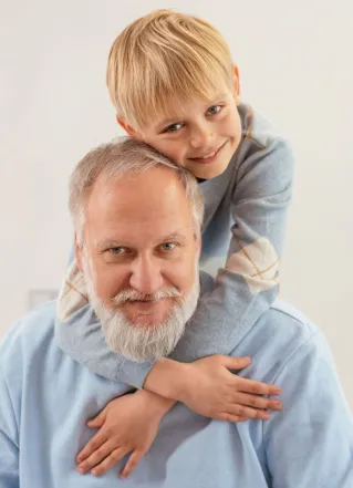 Portrait of a happy grandfather and grandson embracing indoors with a white background.