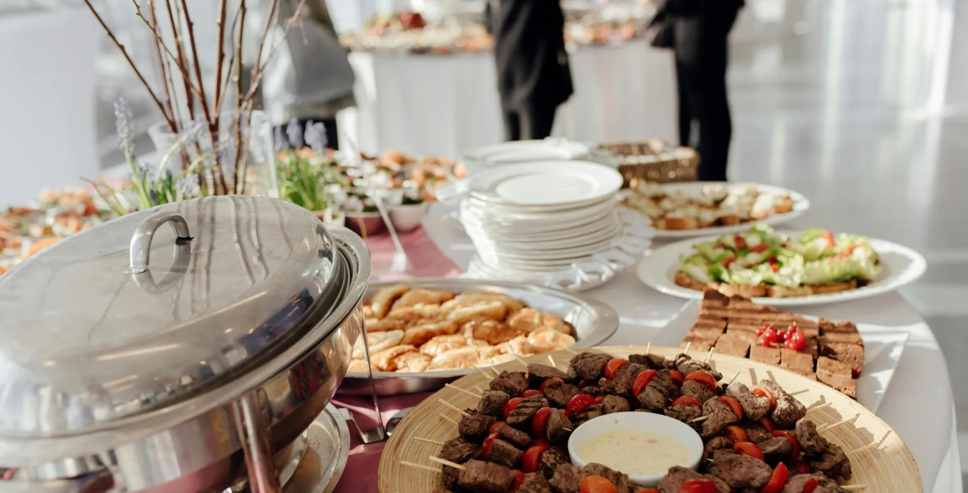 Elegant buffet featuring skewered meats, fresh salads, and assorted desserts at a festive event.
