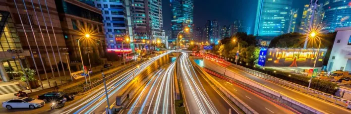 Dynamic long exposure night shot of urban cityscape with vibrant light trails and towering skyscrapers.