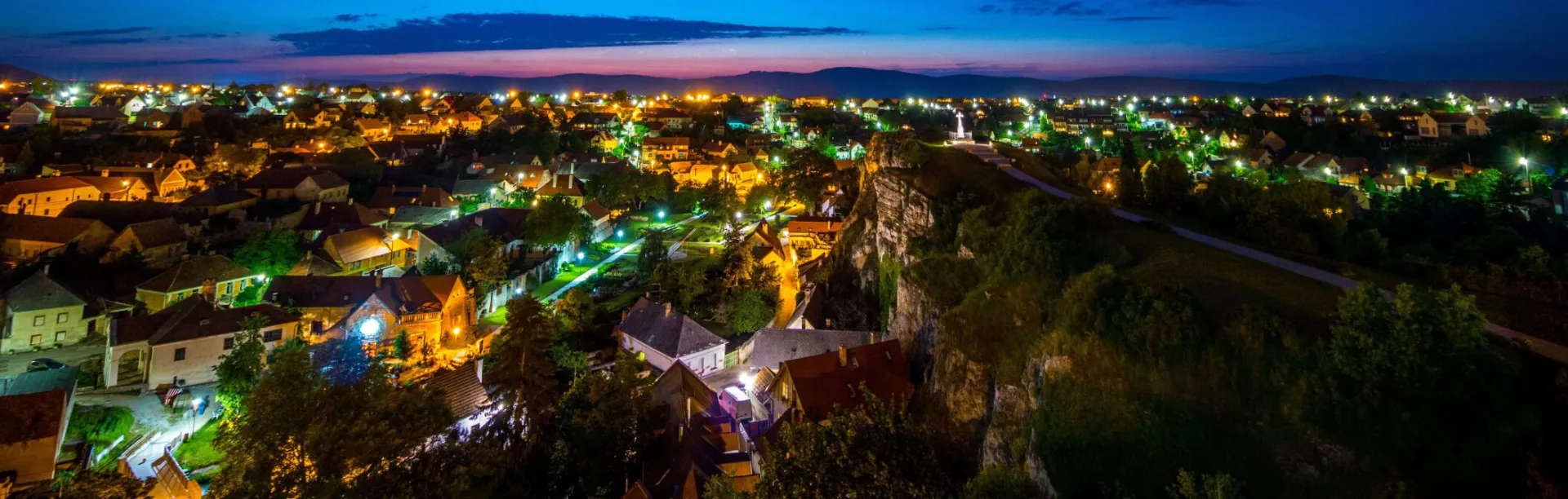 A captivating aerial view of a small town illuminated under a twilight sky, showcasing vibrant lights.