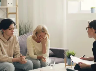 Emotional family therapy session with a therapist indoors, conveying connection and support.