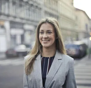 Confident businesswoman smiling outdoors in urban Budapest setting.