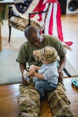 A heartwarming scene of a soldier father playing with his child indoors, showing family warmth.