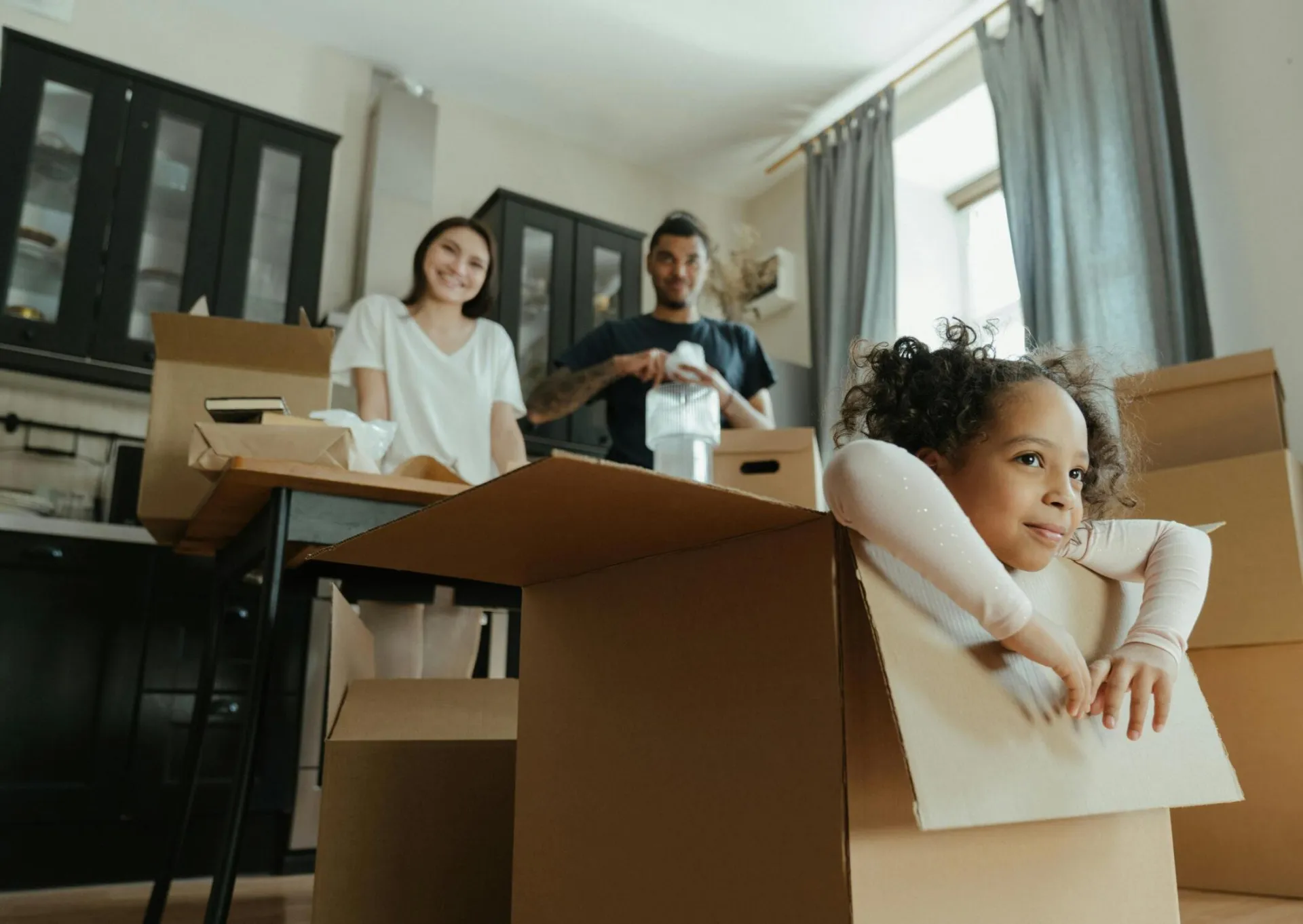 Family enjoys a joyful moment while unpacking boxes in their new kitchen.