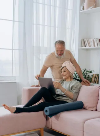 Happy senior couple enjoying leisure time at home using a laptop on the sofa.
