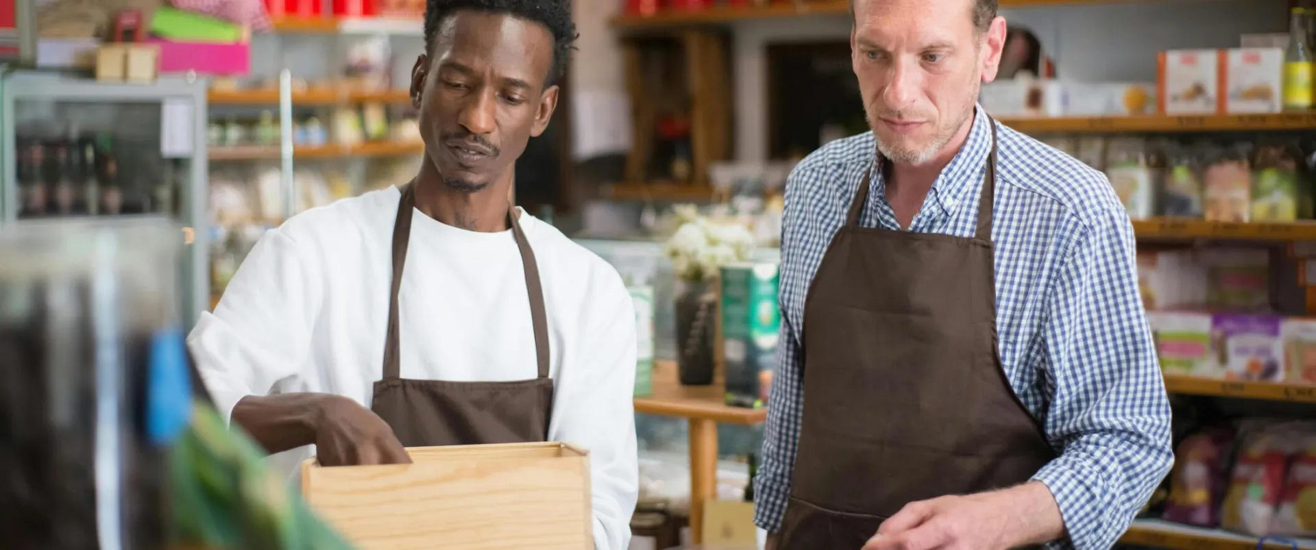 Two male employees organizing products in a cozy grocery store.