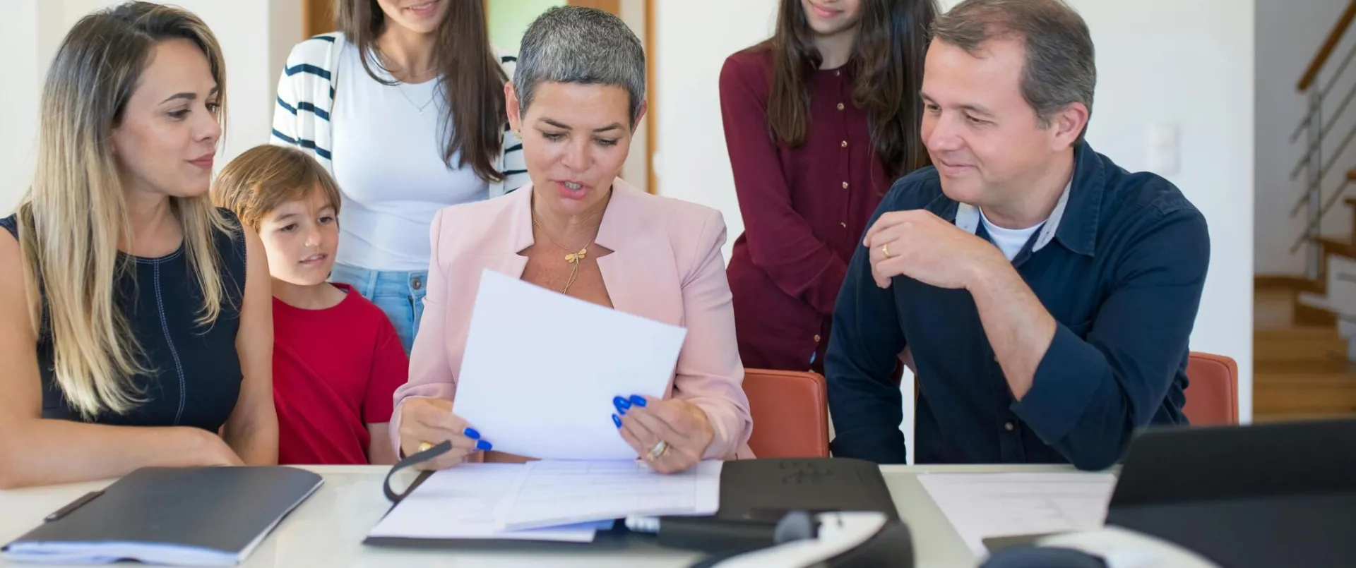 A family meeting with a female realtor reviewing documents in a bright, modern room.