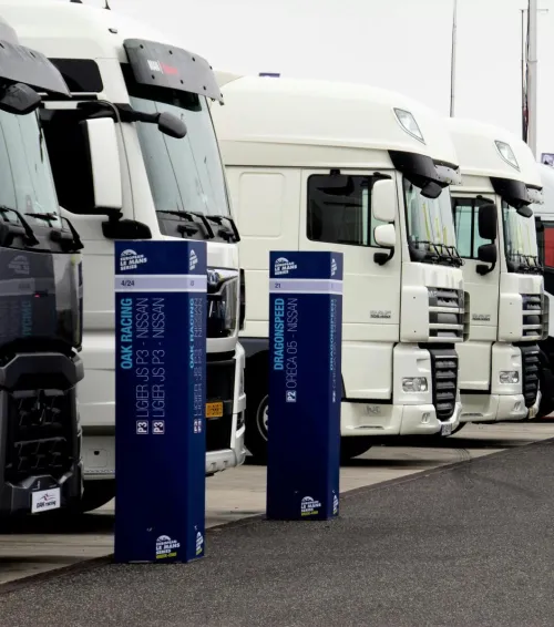 Line of racing trucks with bollards at event in Estoril, Portugal.
