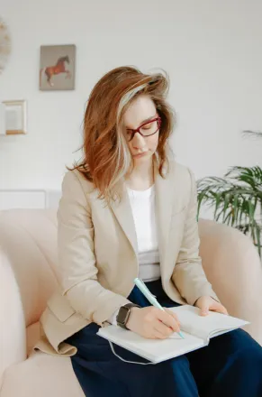 A female therapist taking notes during a session in a stylish office setting.