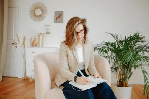 A female therapist taking notes during a session in a stylish office setting.