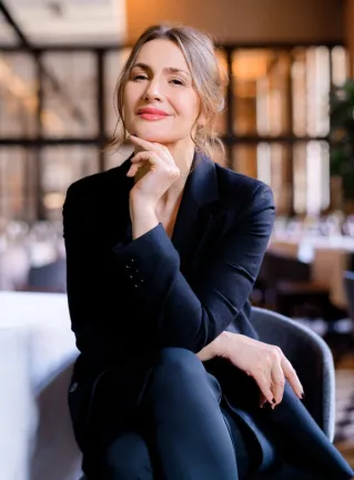 Smiling receptionist at a salon front desk, welcoming clients with a friendly demeanor.