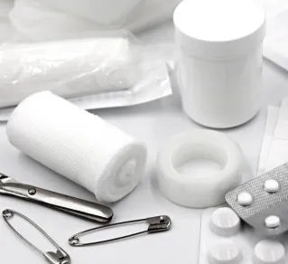 A detailed arrangement of essential first aid supplies including bandages, safety pins, and medication.