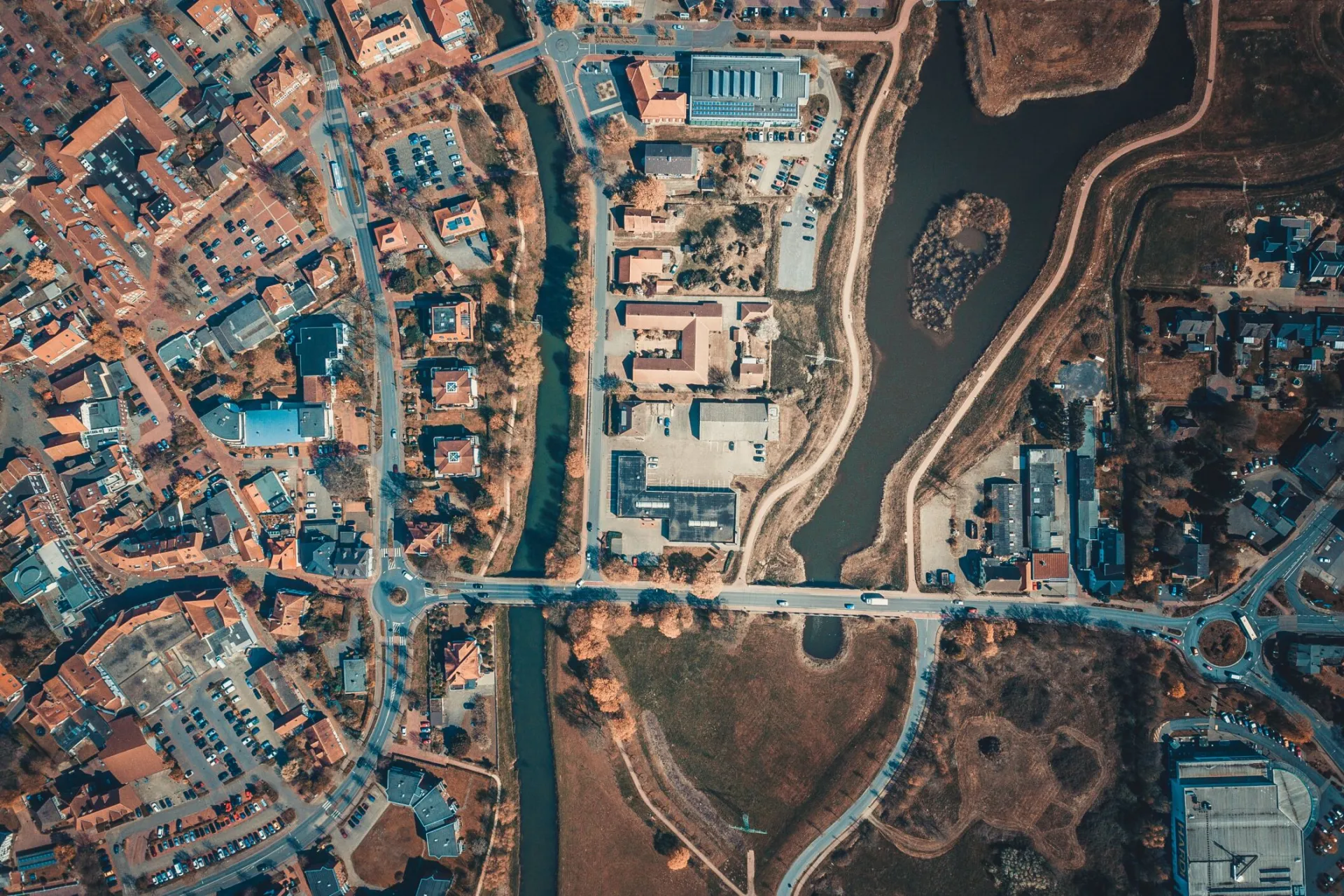 Aerial shot capturing the intricate city layout with roads, buildings, and a body of water.