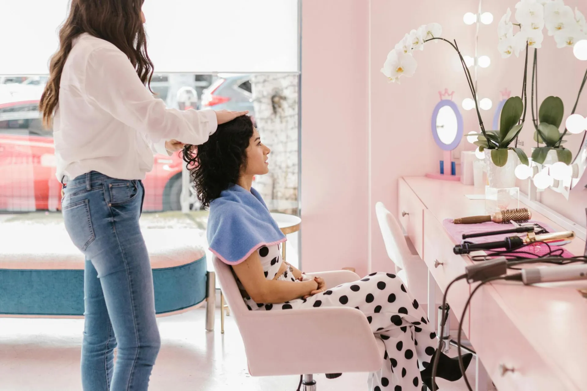 Hairdresser styling client's hair in a modern salon setting with soft lighting.