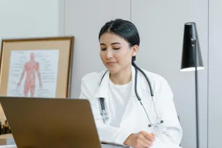 Young female doctor with stethoscope consulting online from office.