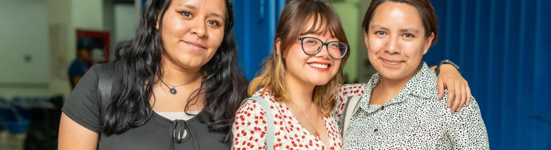 Three friends posing happily together indoors, showcasing friendship and joy.