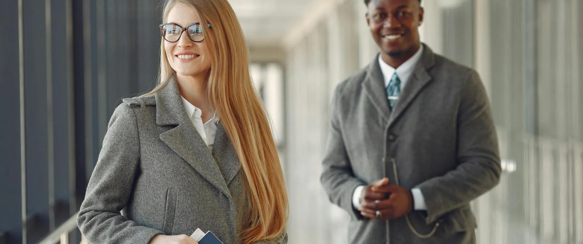 Professionals smiling in an airport terminal, ready for business travel.