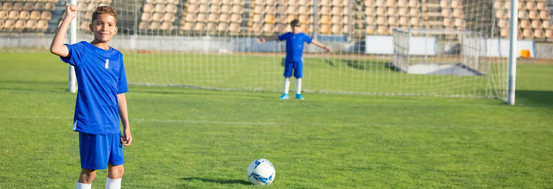 Two young boys playing soccer on a grassy field under clear skies. Perfect for sports themes.