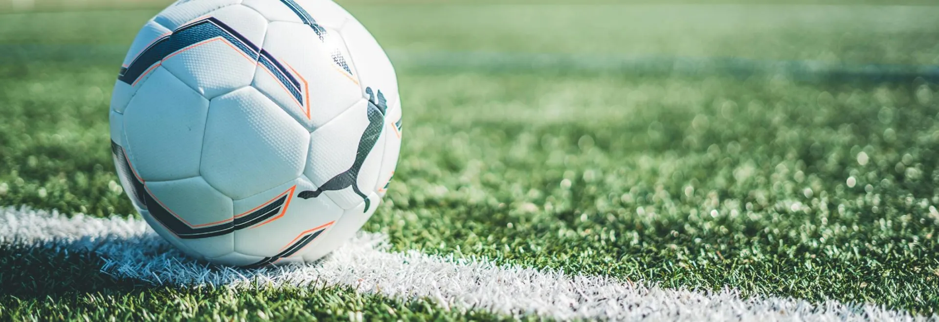 Soccer ball resting on white line of a green grass field. Perfect for sport themes.