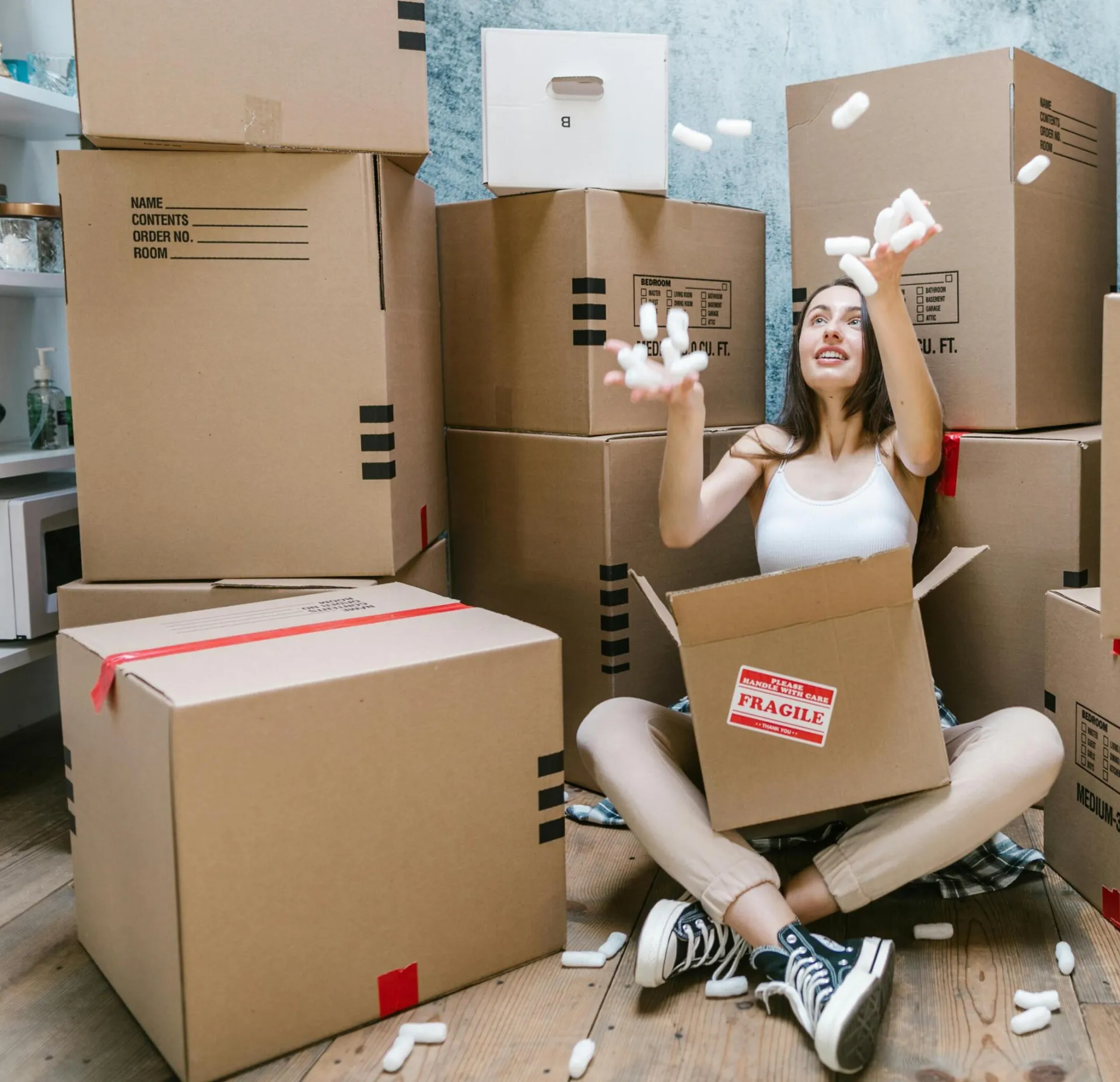 Young woman surrounded by cardboard boxes, happily moving into her new apartment.