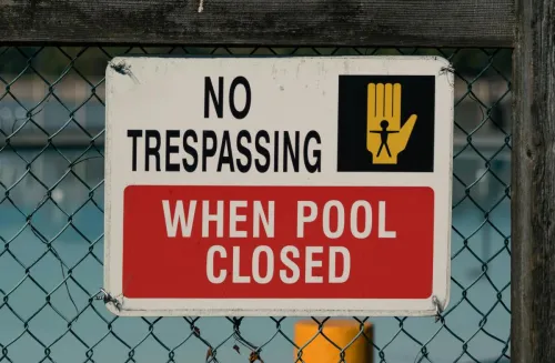 A 'No Trespassing' sign on a chain link fence at a closed swimming pool, ensuring safety and security.