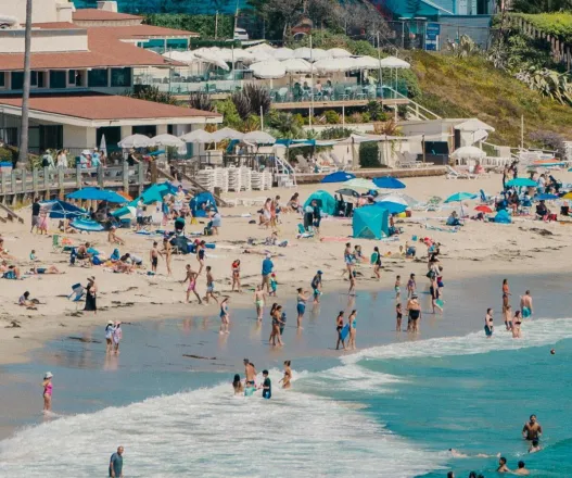 A vibrant beach scene at Laguna Beach, CA, with tourists enjoying the sunny day.