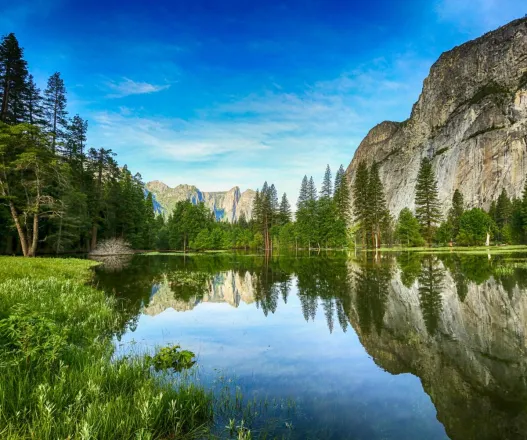 Stunning reflection of mountains and trees in Yosemite Valley's Mirror Lake during daytime.