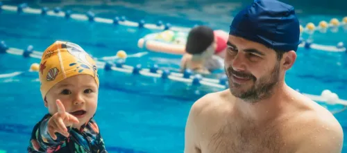 Father and child bond during a swimming lesson at an indoor pool.