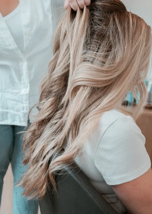 A hairstylist adorns a bride's hair with floral accessories in a chic salon setting.