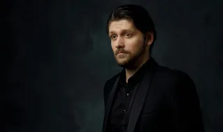 Stylish portrait of a man in black suit on a dark background, showcasing elegance and sophistication.