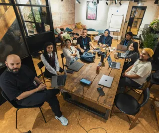 A group of diverse professionals collaborating in a modern office setting with laptops and technology.