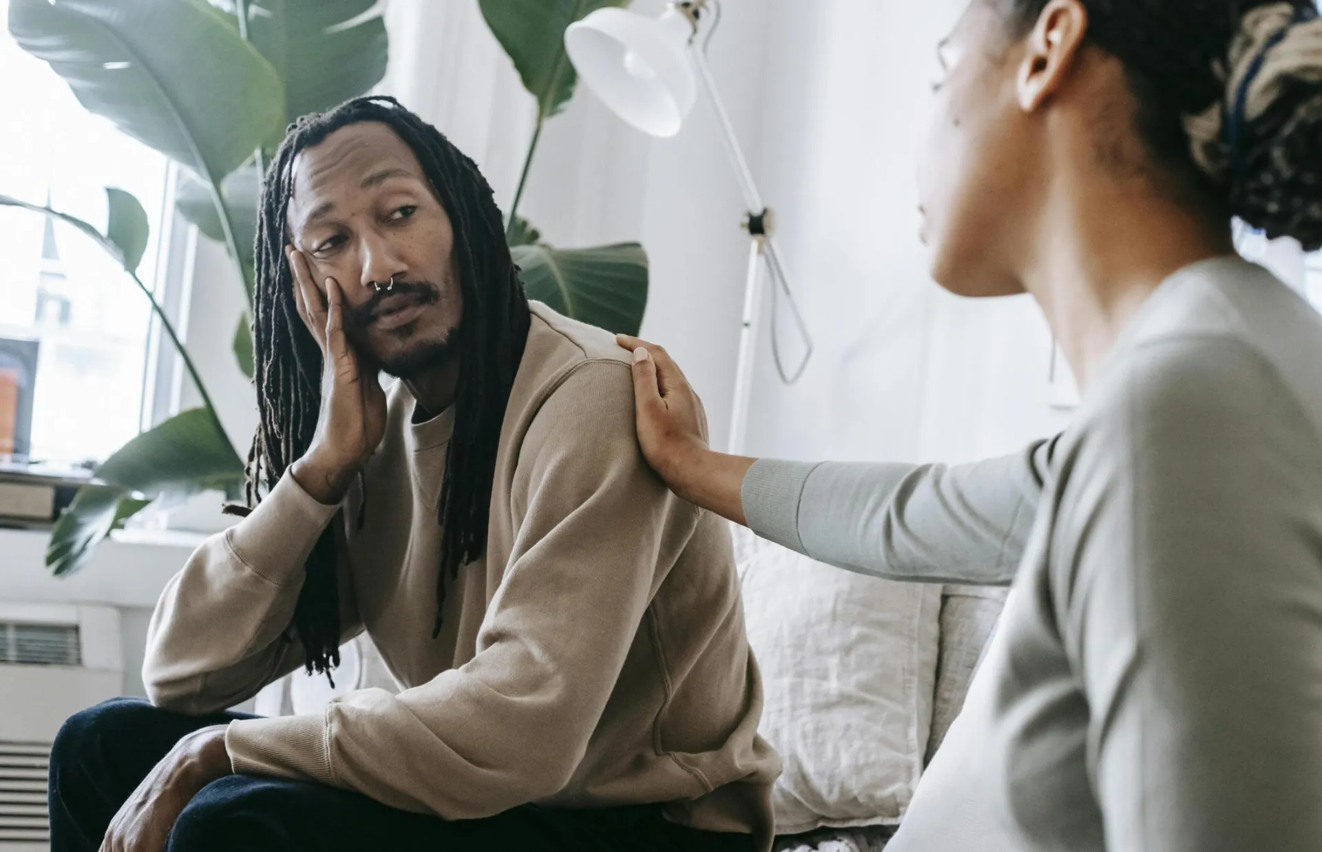 Two diverse individuals having an empathetic conversation in a cozy indoor setting.