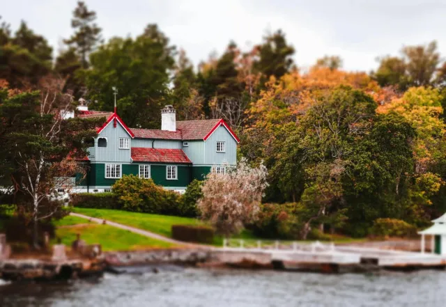 A picturesque Swedish house surrounded by autumn foliage and a serene river.