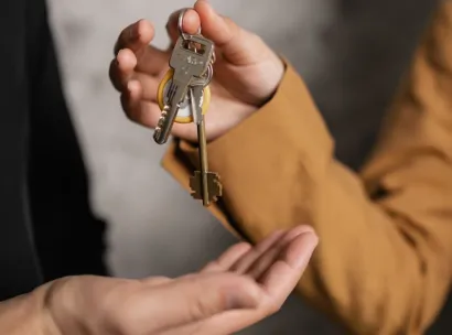 Two adults exchanging house keys, symbolic of property transfer or rental agreement.