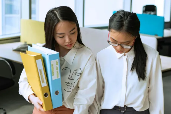 Two professionals reviewing documents in a modern office setting, focusing on teamwork.