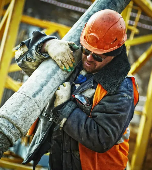Construction worker in safety gear handling equipment on an active site.