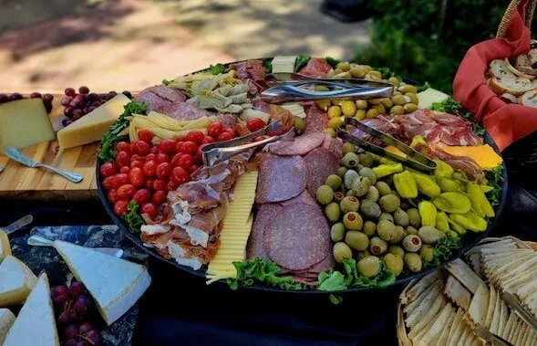 A person serves a variety of foods from a buffet station onto their plate.