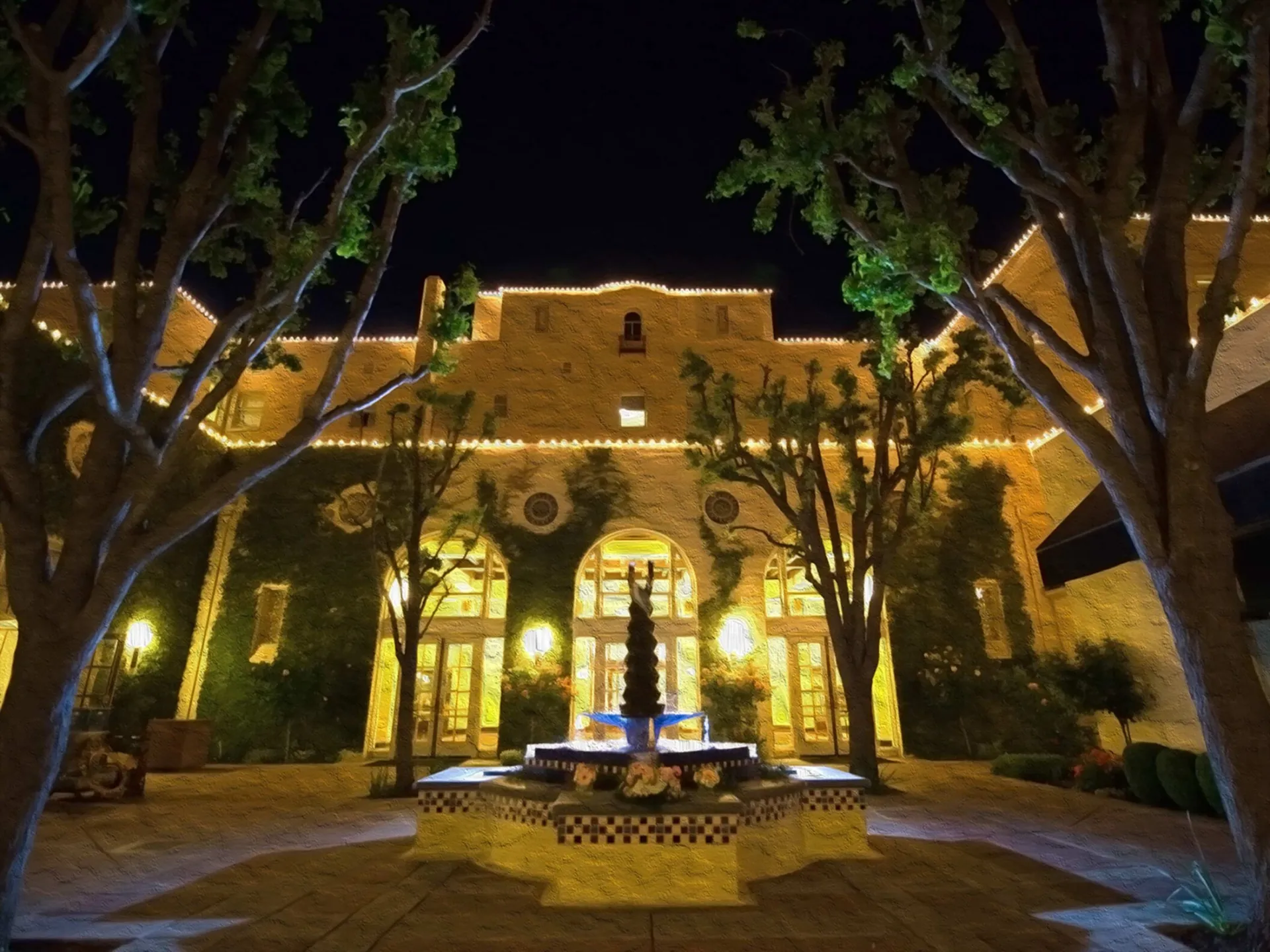 An elegant outdoor wedding venue setup with white floral arches and chairs.