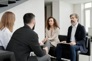 Four professionals engaged in a serious business discussion indoors.