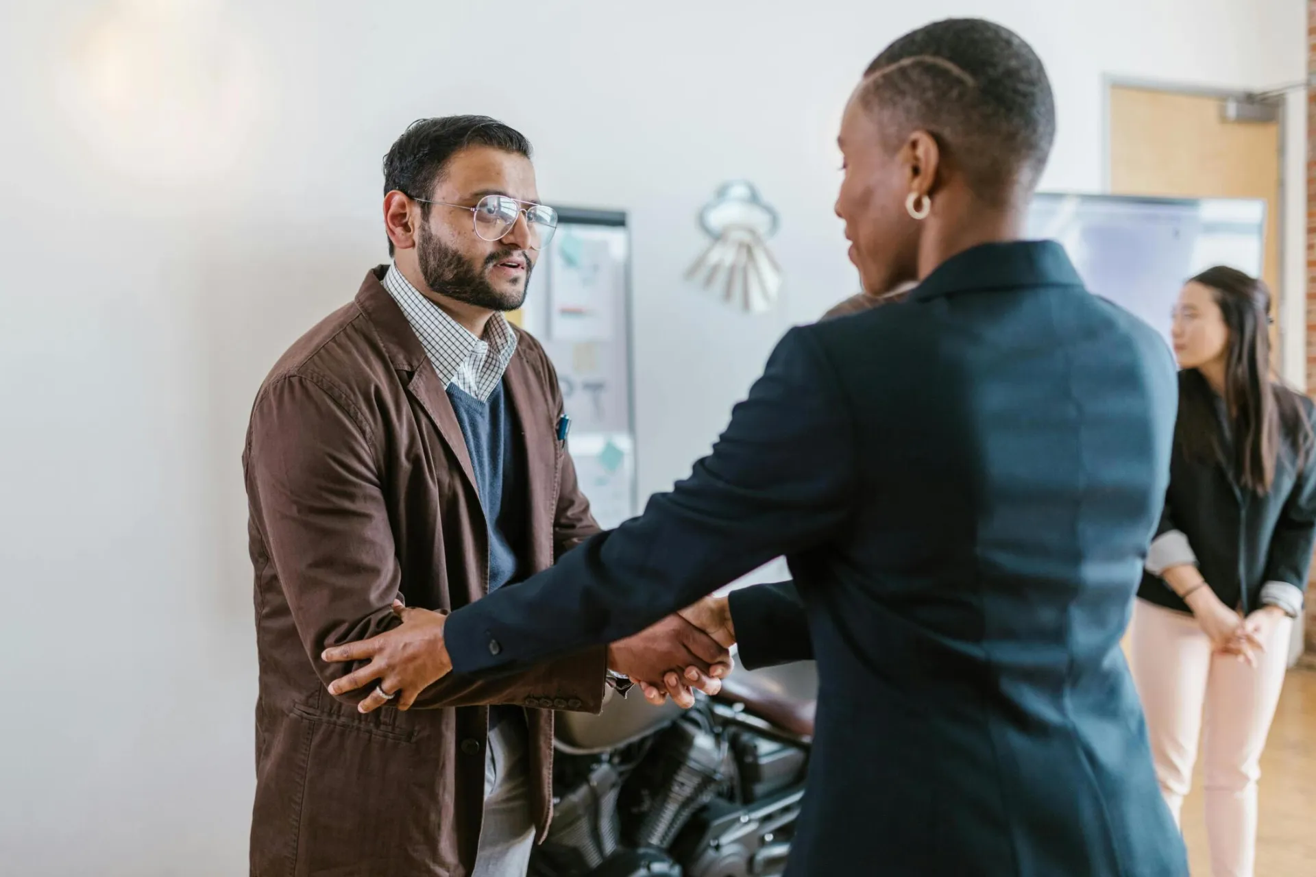 Business professionals greeting with a handshake in an office setting, promoting teamwork and cooperation.