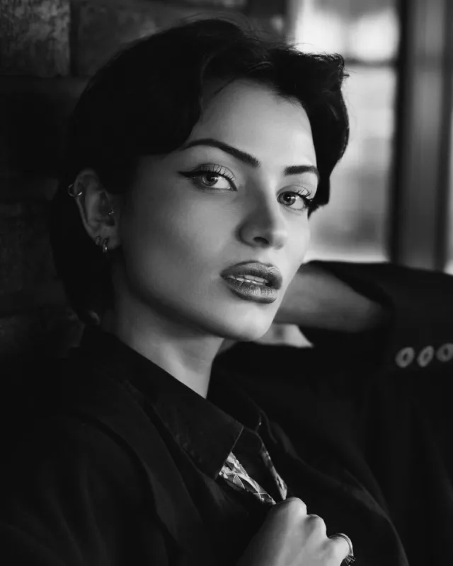 Artistic black and white portrait of a woman with short hair, looking at the camera.