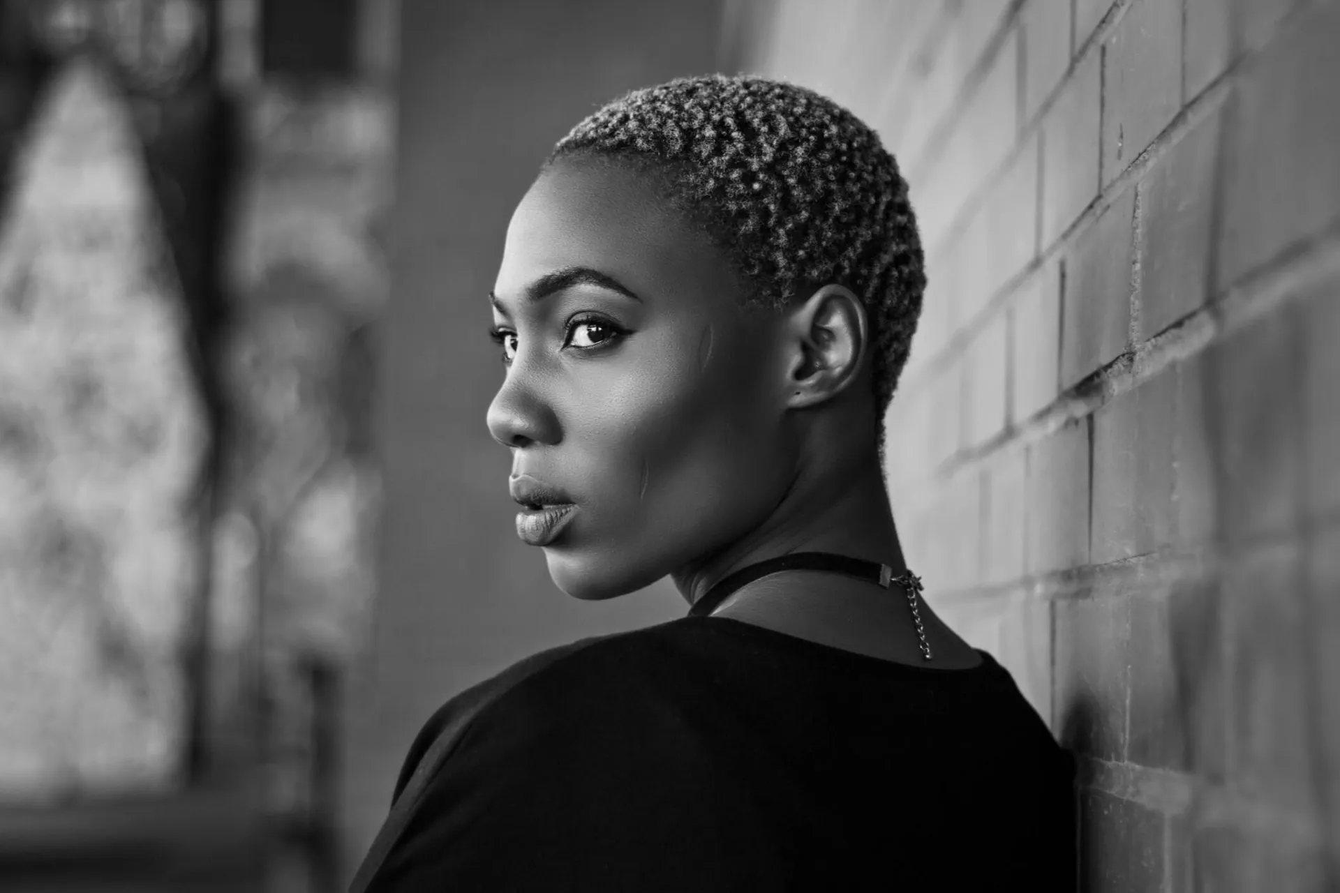 Black and white portrait of a woman with short hair by a wall in Johannesburg, South Africa.