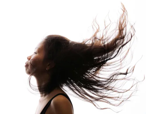 A high-contrast profile of a woman with her hair flowing, showcasing movement and expression.