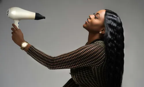 Elegant African American woman in New Orleans blow drying her hair, showcasing modern style.