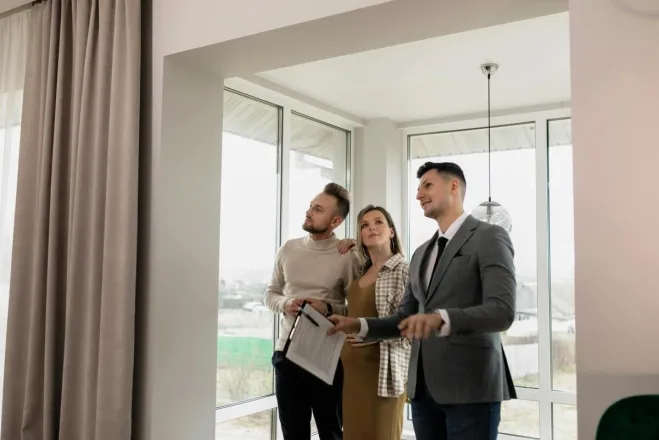 A real estate agent showing a modern home to a young couple during a daytime viewing.