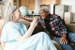 Joyful elderly couple sharing a warm moment at home, smiling and talking.