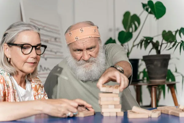 Senior couple playing Jenga, focused and happy indoors, enjoying a relaxing afternoon.