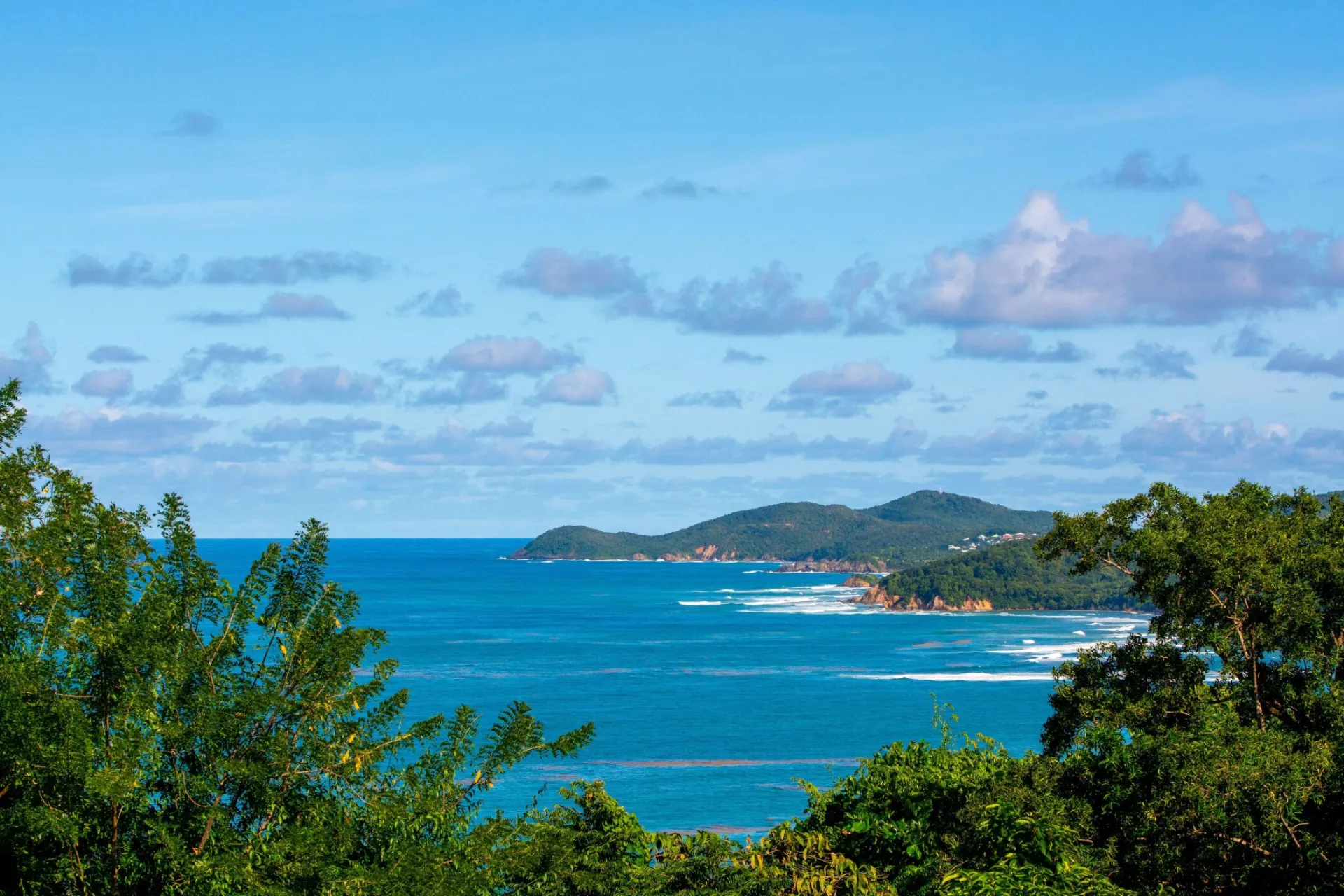 A breathtaking view of a tropical island with lush greenery and vibrant blue ocean under a clear sky.