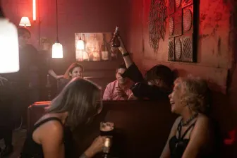 Group of friends enjoying a lively night out at a trendy bar with drinks and laughter.